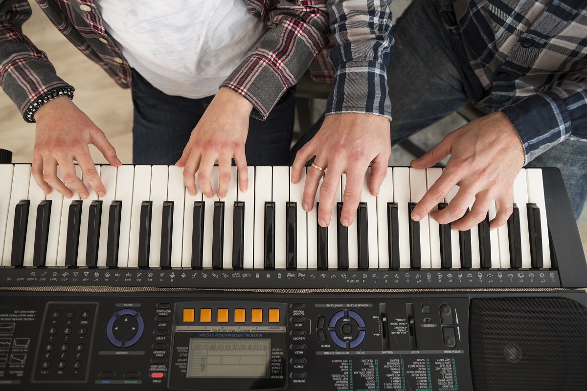 Mãos de pessoas tocando teclado musical